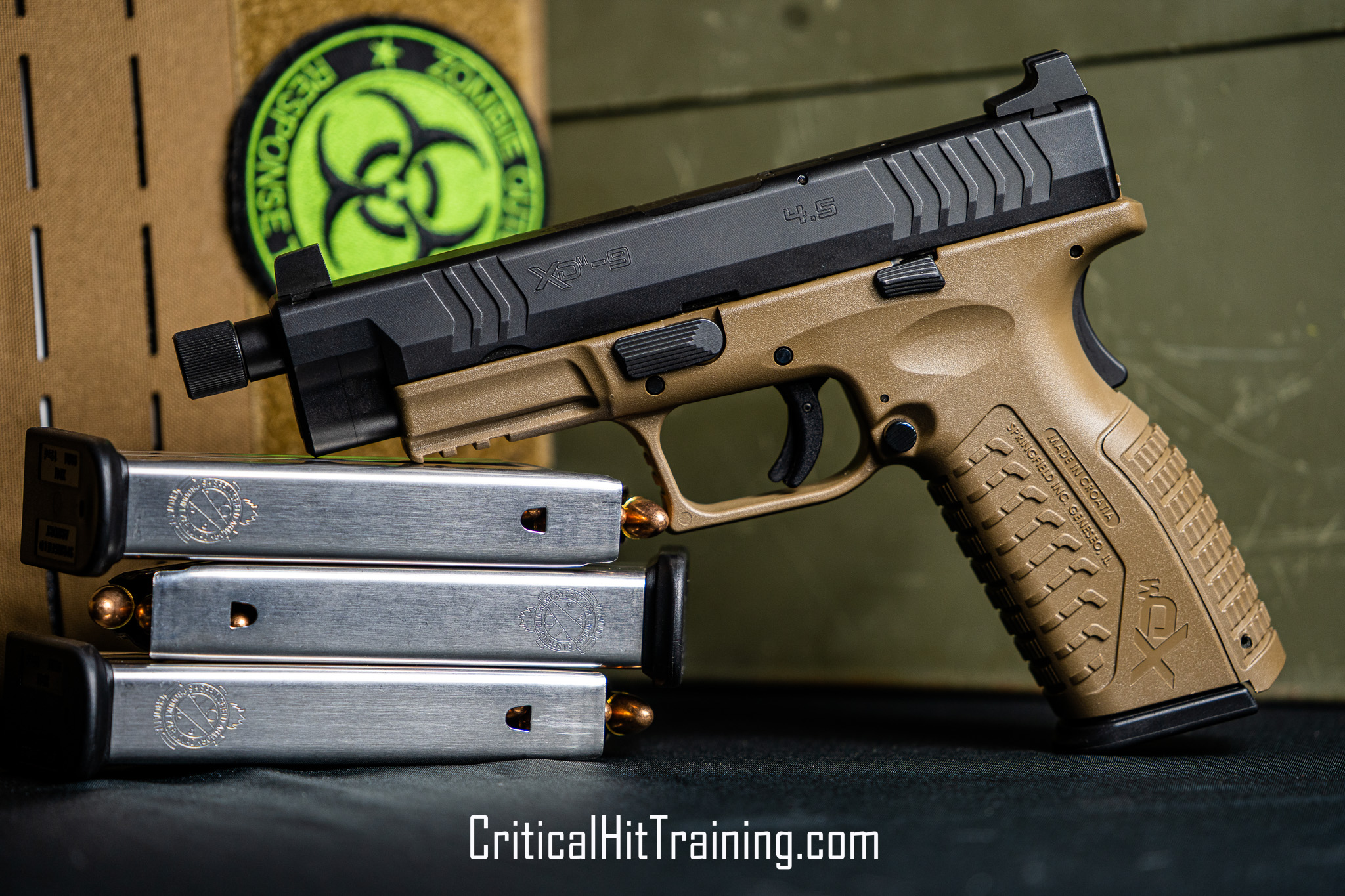 Image of a Springfield XDM-9 pistol displayed in front of stacked military-style ammo cans, highlighting the firearm's sleek design, textured grip, and tactical setting.